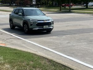 Car driving on newly paved concrete with visible sensor wires emerging from the surface