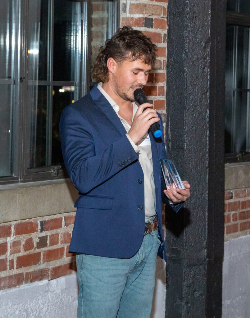 Adam Bier holding his Rising Star Award at the Horner and Shifrin holiday party.