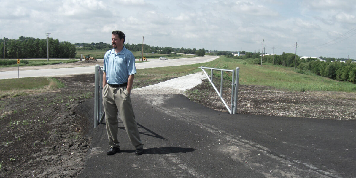 Jarrett Jasper, PE, stands beside a newly constructed multi-use trail along a Missouri highway during a transportation infrastructure project.